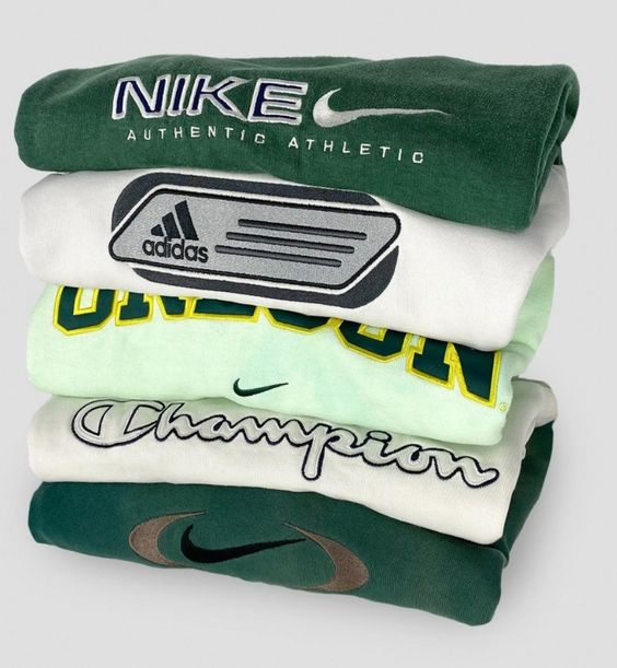 Pila de sudaderas vintage Nike, Adidas, Champion y Oregon en tonos verdes.